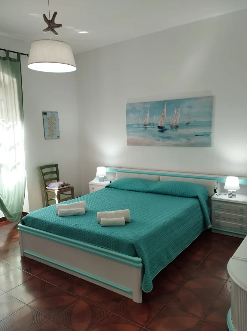 La camera matrimoniale con il copriletto turchese e il quadro delle barche a vela