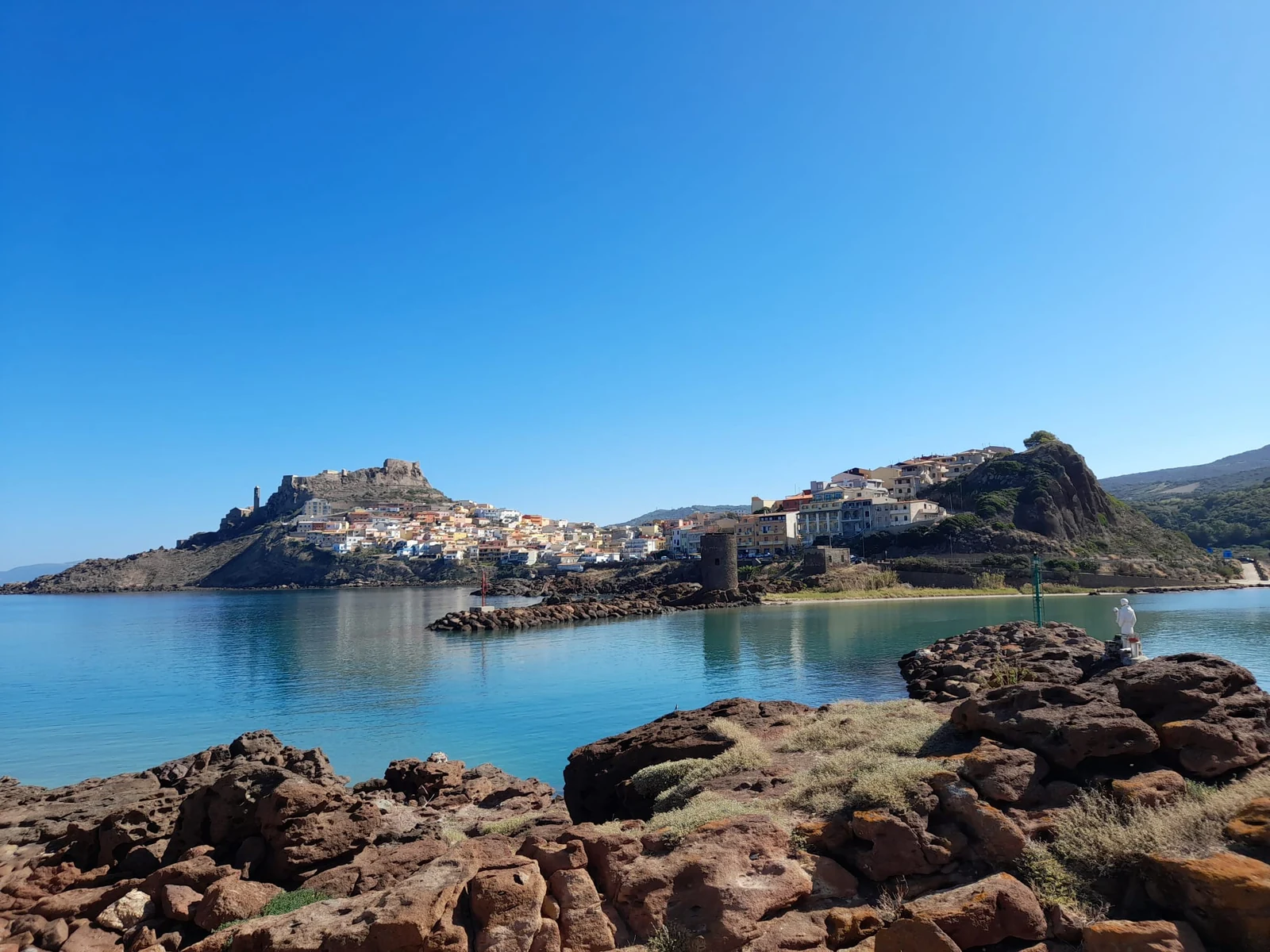 Castelsardo vista dalla scogliera, con il borgo e il castello sul promontorio e il mare calmo