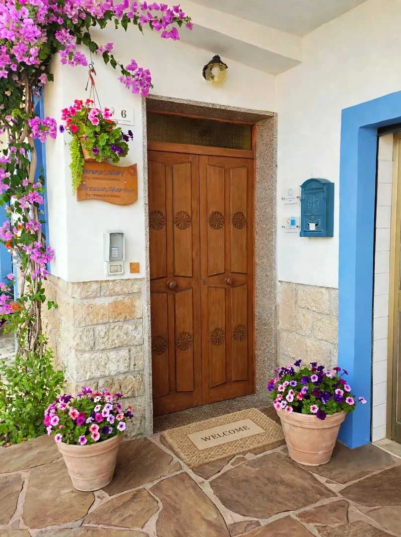 L'ingresso con il portone in legno, la bouganville e i vasi fioriti