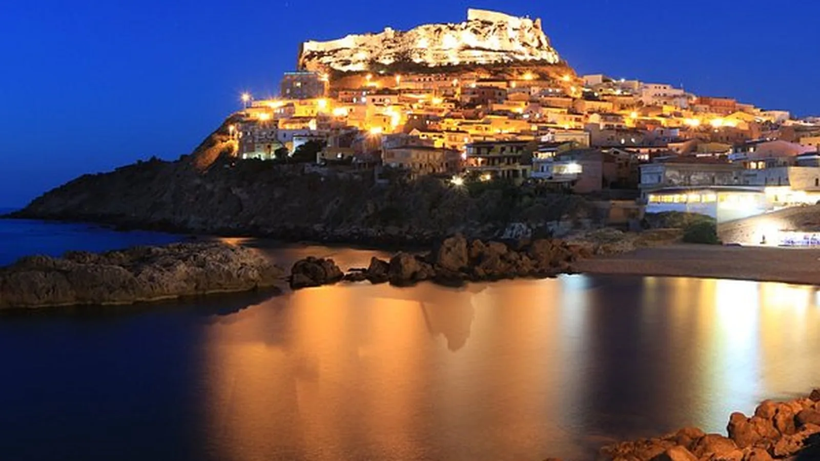 Grande falò di Sant'Antonio Abate acceso di notte nella piazza di un paese sardo